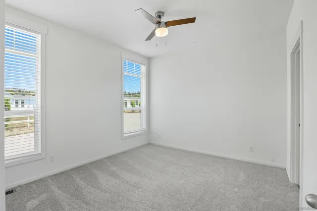an empty room with windows and fan