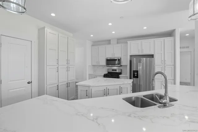 a kitchen with stainless steel appliances a refrigerator sink and white cabinets