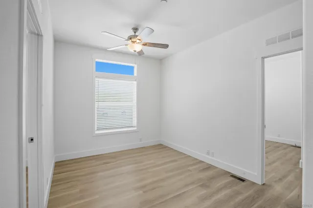 an empty room with wooden floor and chandelier fan