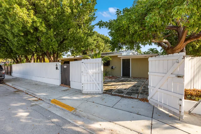 a view of backyard with large tree and wooden fence
