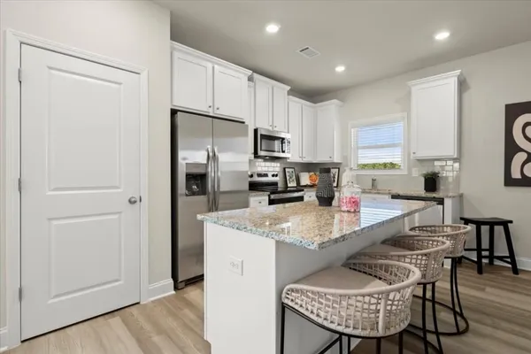 a kitchen with stainless steel appliances granite countertop a stove a refrigerator a sink a dining table and chairs