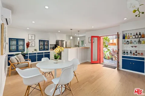 a kitchen with stainless steel appliances granite countertop a refrigerator a microwave a dining table and chairs with wooden floor