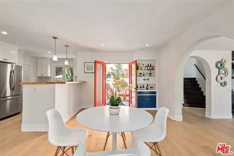 a kitchen with stainless steel appliances a stove a sink dishwasher a dining table and chairs with wooden floor