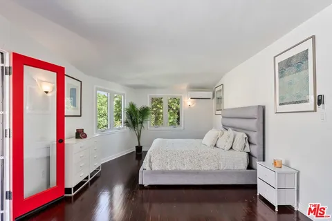 a spacious bedroom with a bed and a dresser with wooden floor