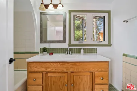 a bathroom with a sink and mirror with bathtub