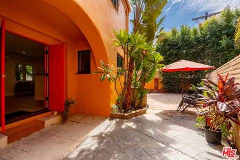 a balcony with table and chairs and potted plants