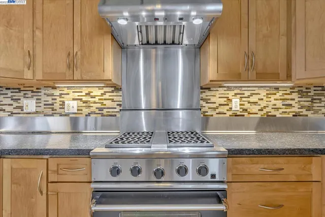 a bathroom with stainless steel appliances granite countertop a sink and wooden cabinets
