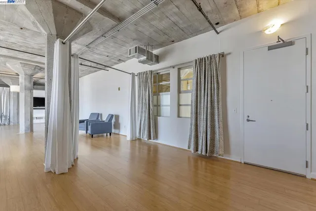 a view of a big room with wooden floor and windows