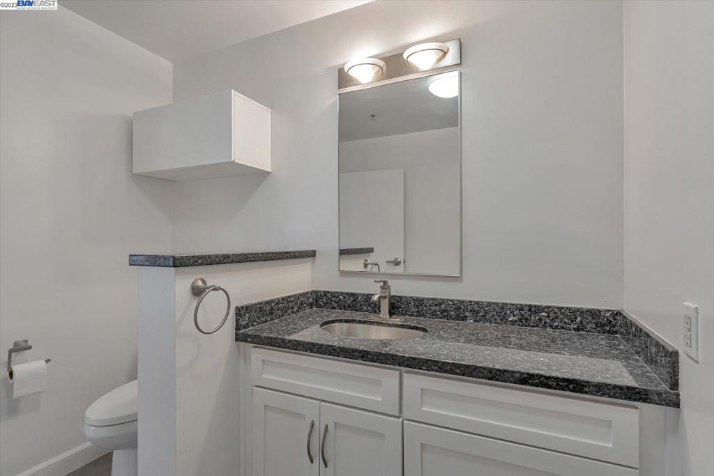 737 2nd Street, Unit 310 Oakland, CA 94607 - Photo 26 of 29 a bathroom with a granite countertop sink a toilet and a mirror