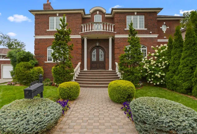 a view of a brick house with potted plants and a large tree