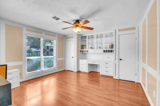 a view of empty room with wooden floor and fan