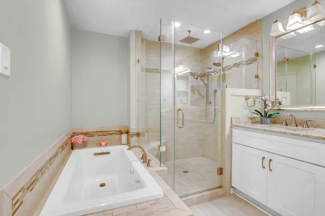a bathroom with a tub sink vanity and mirror