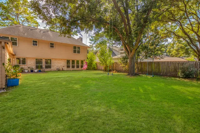 a view of a white house in front of a big yard with large trees