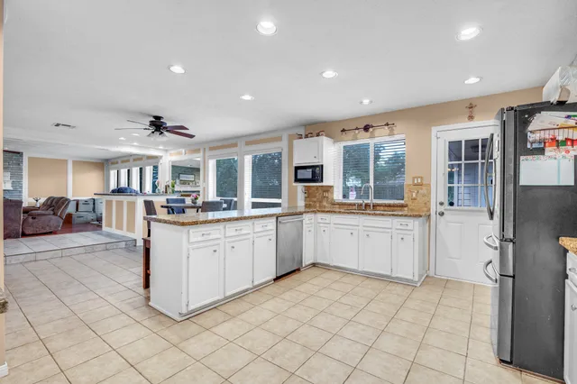 a kitchen with stainless steel appliances kitchen island granite countertop a refrigerator and cabinets