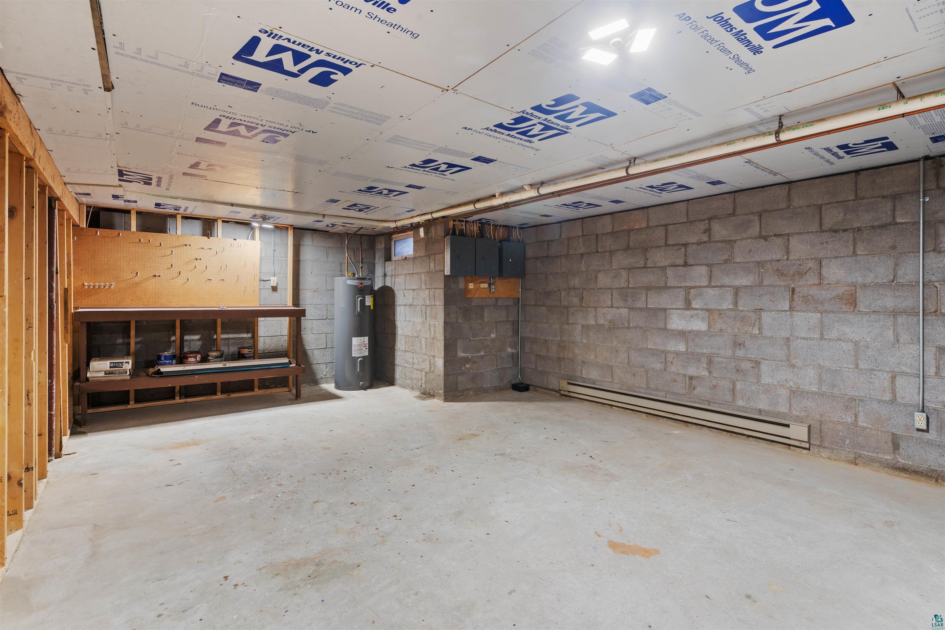 5373 Lester River Road Duluth, MN 55804 - Photo 30 of 39 Concrete floor, exposed block walls, visible insulation panels, utility water heater, and a built-in workbench
