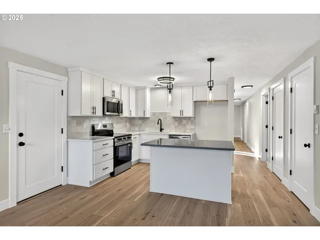 a kitchen with stainless steel appliances cabinets a sink and a wooden floor