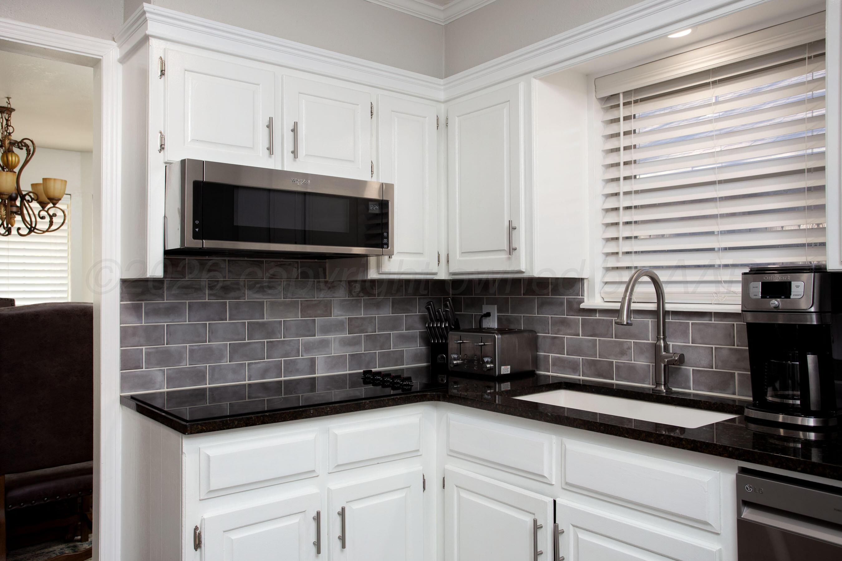 7924 Simpson Drive Amarillo, TX 79121 - Photo 9 of 33 a kitchen with stainless steel appliances white cabinets and a stove top oven