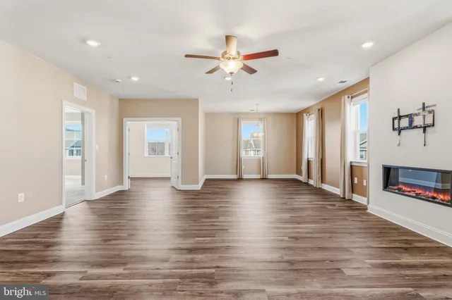 a view of an empty room with window and wooden floor