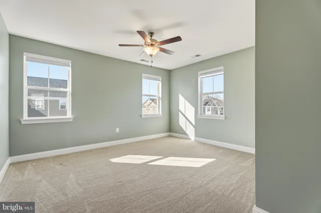 an empty room with windows and fan