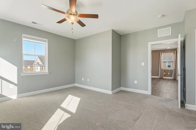 a view of empty room with window and ceiling fan