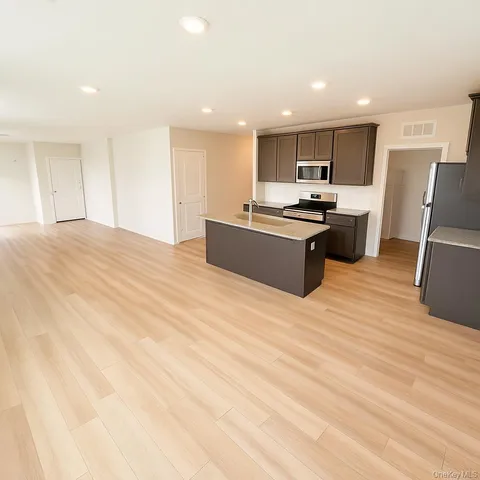 a large kitchen with stainless steel appliances kitchen island a large counter top and a stove top oven with wooden floor