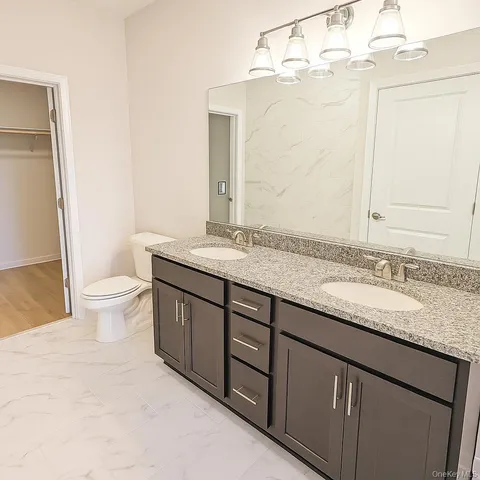 a bathroom with a granite countertop sink a toilet and a mirror