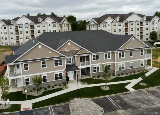 a view of a white house next to a yard with potted plants