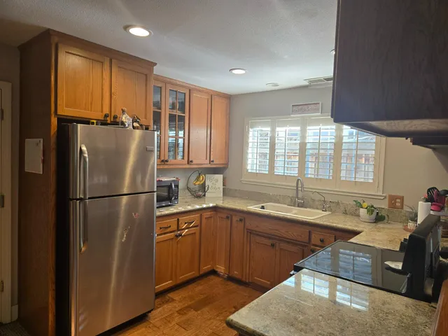 a kitchen with stainless steel appliances granite countertop a refrigerator a sink dishwasher a stove and a refrigerator