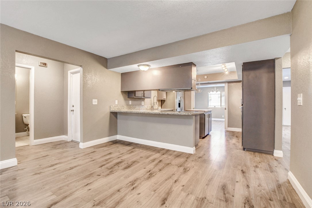 4367 South Mojave Road Las Vegas, NV 89121 - Photo 18 of 53 Laminate flooring connects an open-concept living area to a sleek, modern kitchen.