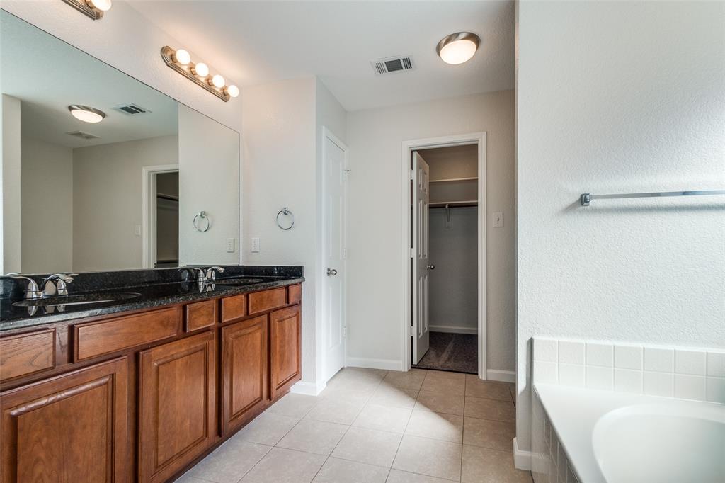 1257 Barrel Run Fort Worth, TX 76052 - Photo 15 of 26 Bathroom featuring a dual-sink vanity with wood-finish cabinetry and granite countertops, large mirror, and recessed tub with white tile surround