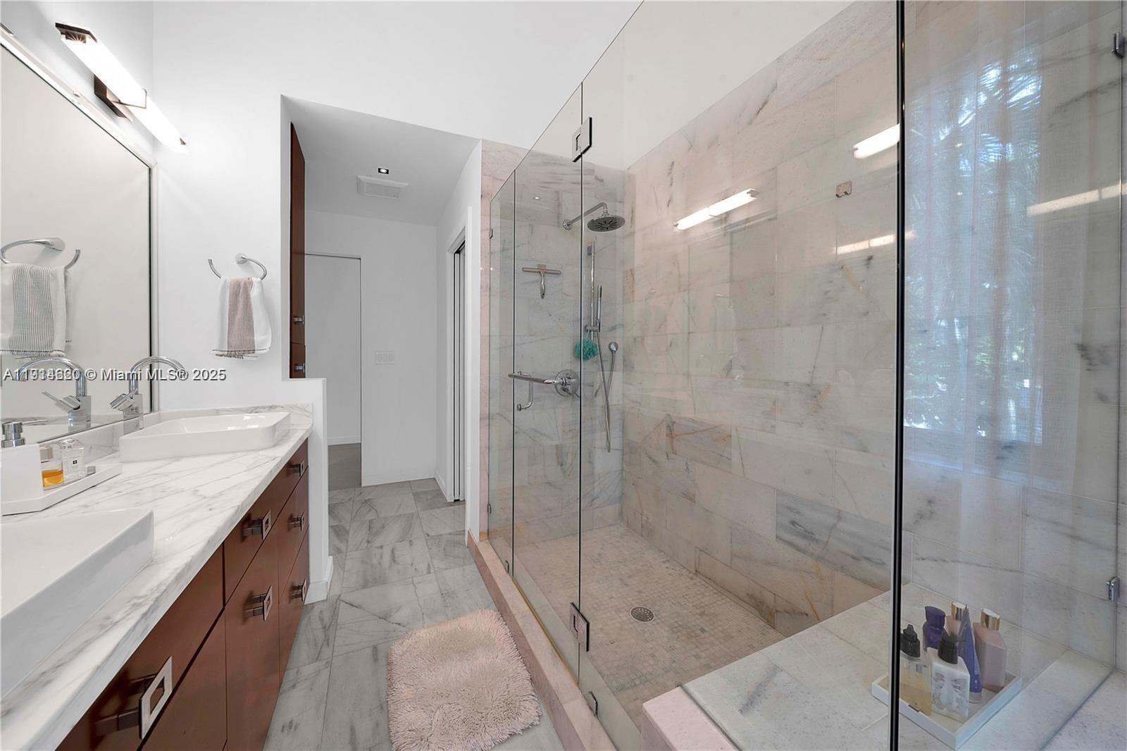 3760 Douglas Road Miami, FL 33133 - Photo 47 of 70 a bathroom with a granite countertop sink a mirror and a shower