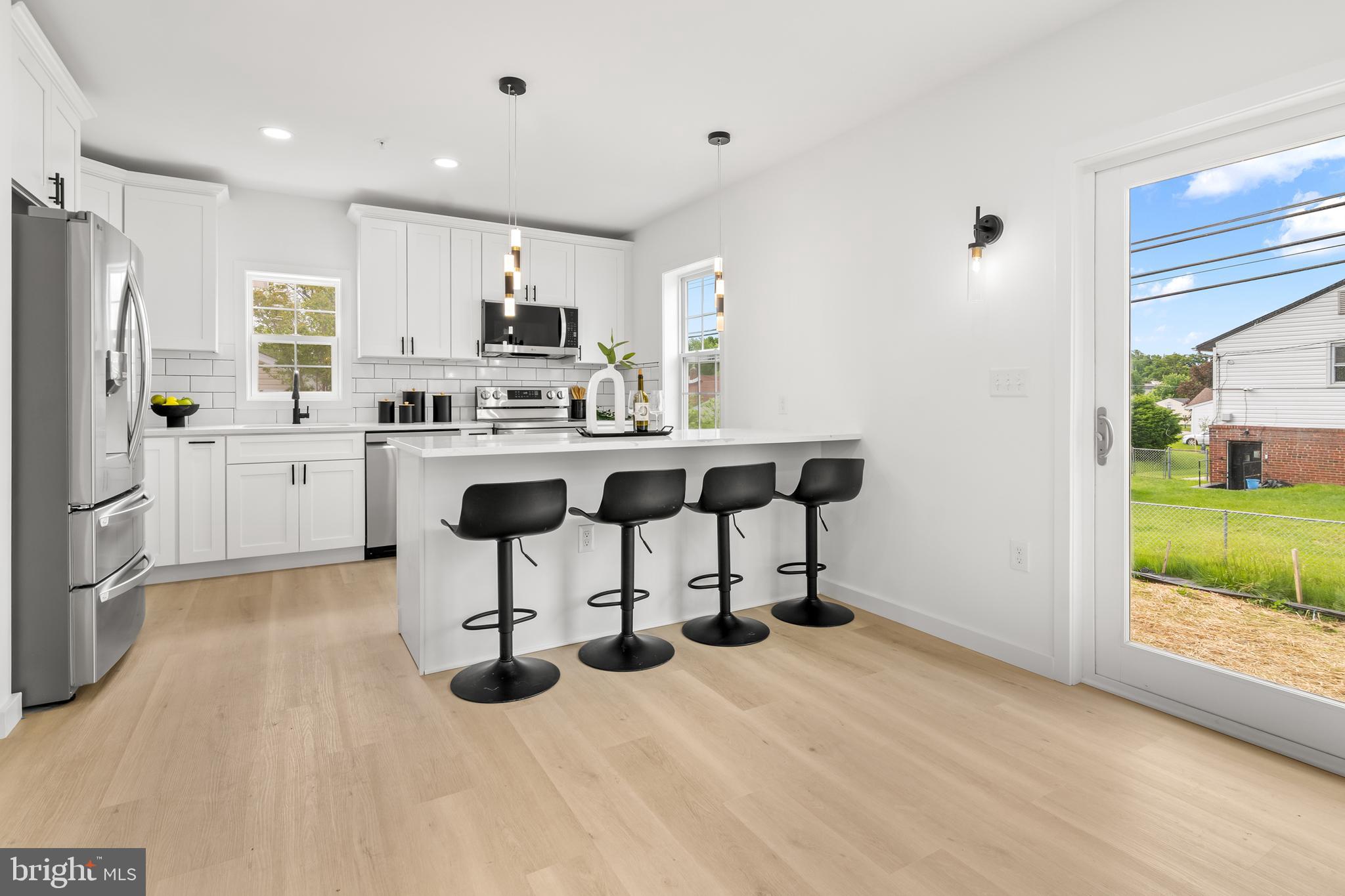 7817 Liberty Road Windsor Mill, MD 21244 - Photo 13 of 50 a kitchen with stainless steel appliances kitchen island granite countertop a table chairs refrigerator and sink