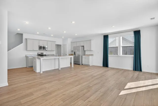 a large kitchen with stainless steel appliances kitchen island a large counter top and a wooden floors