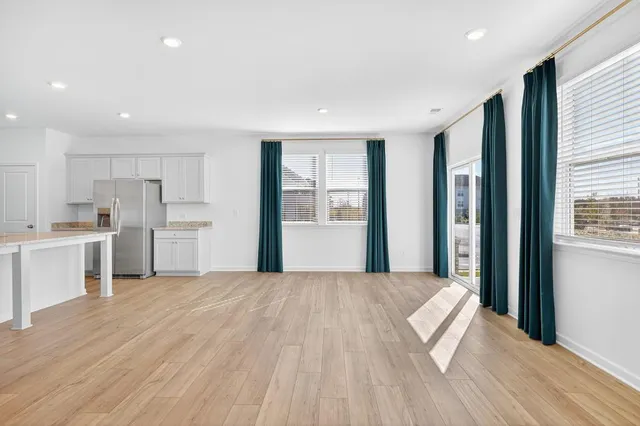 a large white kitchen with kitchen island wooden floors and stainless steel appliances