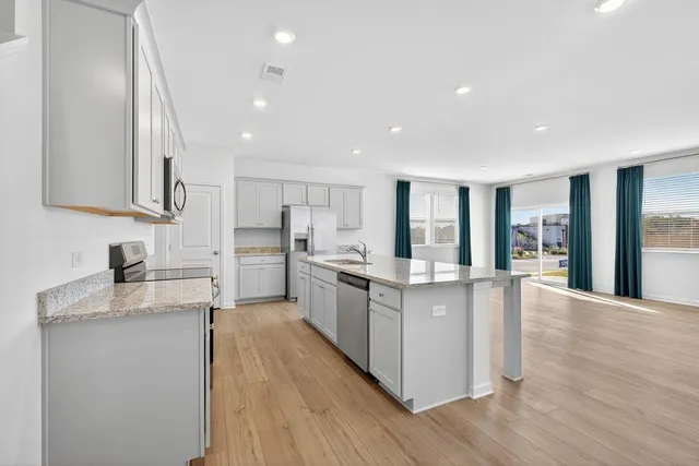 a large kitchen with stainless steel appliances granite countertop a lot of counter space and wooden floors