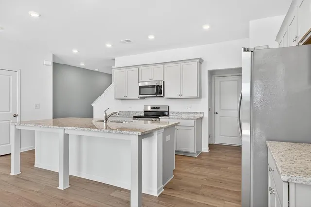 a kitchen with stainless steel appliances granite countertop a refrigerator a sink and a stove