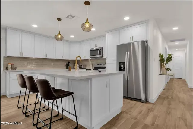 a kitchen with stainless steel appliances granite countertop a refrigerator a stove a sink dishwasher and a refrigerator with wooden floor