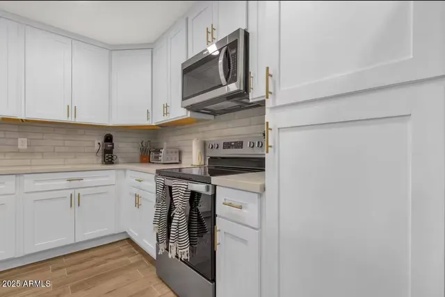 a kitchen with stainless steel appliances granite countertop white cabinets a stove top oven a sink and dishwasher