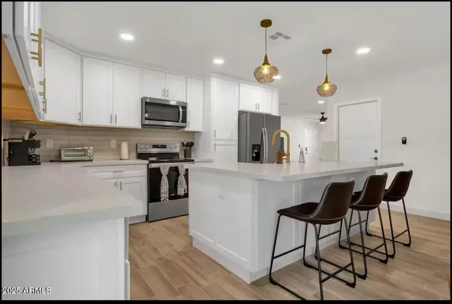 a kitchen with stainless steel appliances kitchen island granite countertop a stove top oven a sink a dining table and chairs