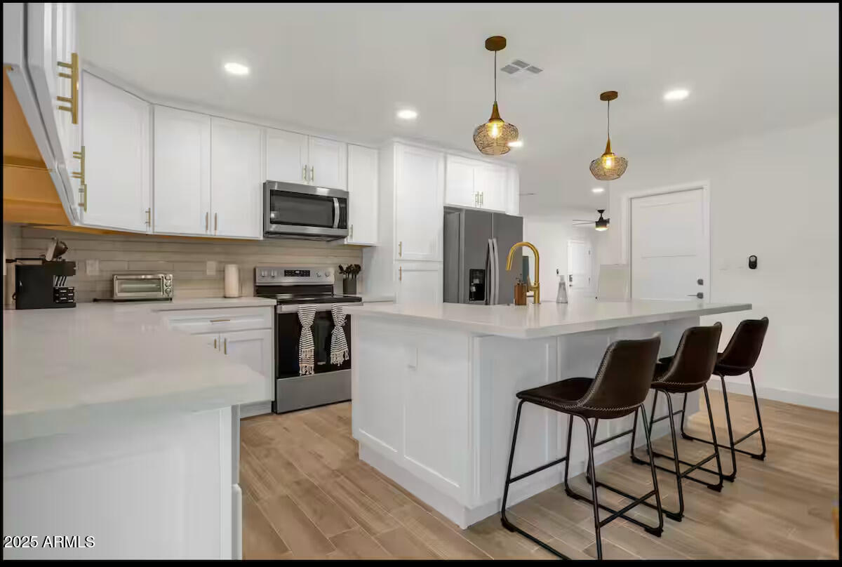 2452 East Manhatton Drive Tempe, AZ 85282 - Photo 3 of 25 a kitchen with stainless steel appliances kitchen island granite countertop a stove top oven a sink a dining table and chairs