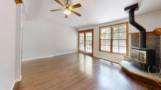 a view of an empty room with a window and wooden floor
