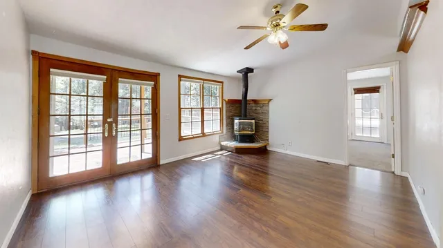an empty room with wooden floor fan and windows