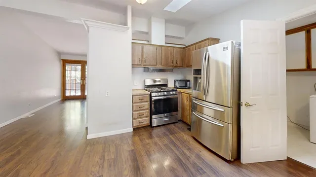 a kitchen with stainless steel appliances a refrigerator and a hard wood floor