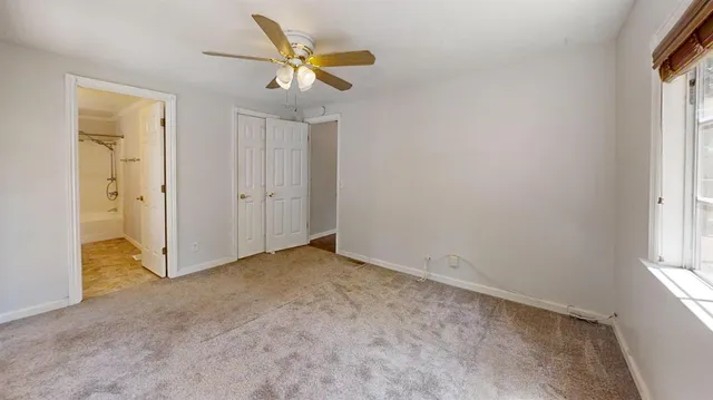 an empty room with a window and a ceiling fan