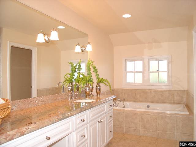 931 La Reno, NV 89509 - Photo 8 of 9 a bathroom with a granite countertop sink a large mirror and a bathtub with shower