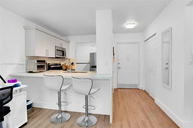 a kitchen with stainless steel appliances a refrigerator a stove a sink dishwasher and white cabinets with wooden floor