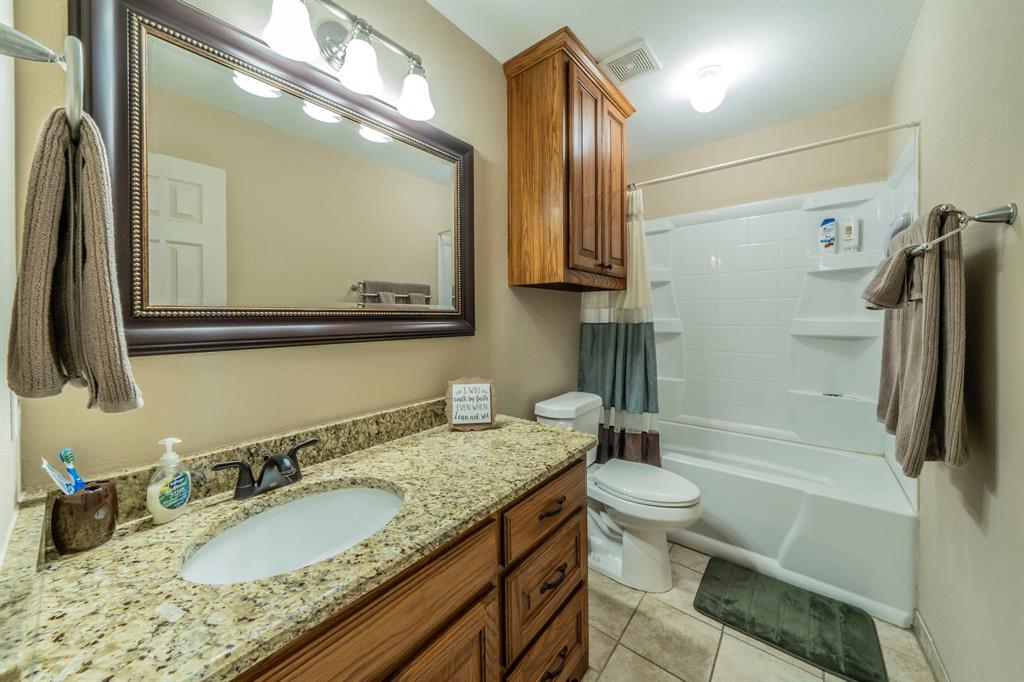 1013 Short Line Boulevard Midlothian, TX 76065 - Photo 16 of 26 a bathroom with a granite countertop sink a mirror and a toilet