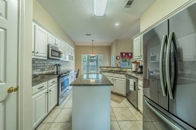 a kitchen with stainless steel appliances granite countertop a refrigerator oven a stove top oven and a sink