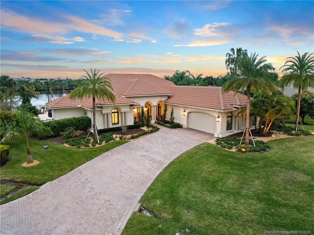12038 Riverbend Road Port St. Lucie, FL 34984 - Photo 24 of 86 a view of a white house in front of a big yard with plants and palm trees