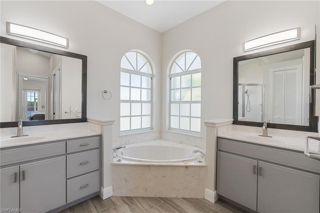 132 Wilderness Cay Naples, FL 34114 - Photo 13 of 24 a spacious bathroom with double vanity a mirror a bathtub and a double vanity sink